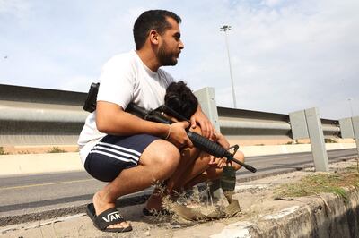 An armed Israeli holds his son as they leave their vehicle to take cover during a rocket attack along a main road in Tel Aviv. AFP