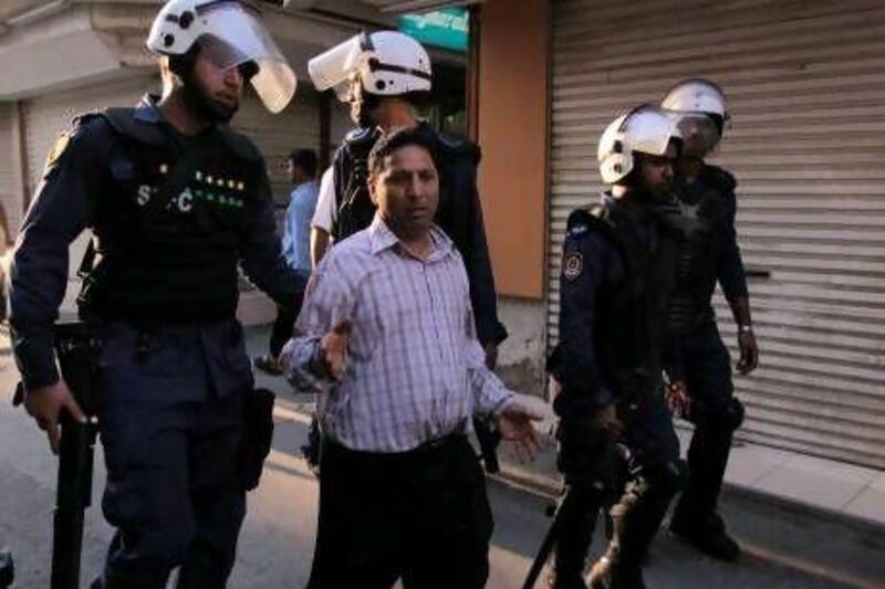 Riot police detain a man while dispersing people gathering at a march in Manama.