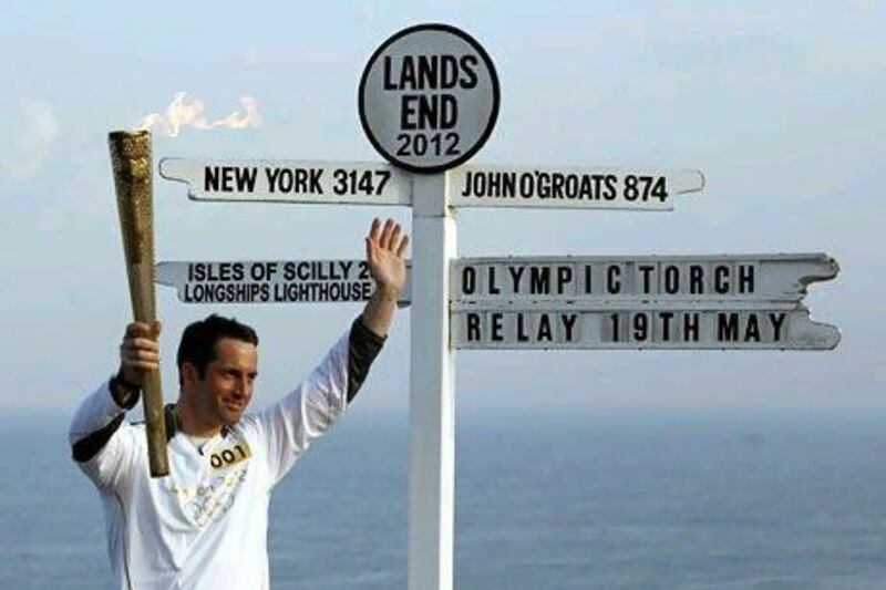 Triple Olympic gold medal-winning sailor Ben Ainslie holds the Olympic torch as the first torchbearer for the London 2012 Olympic Games relay around Britain.