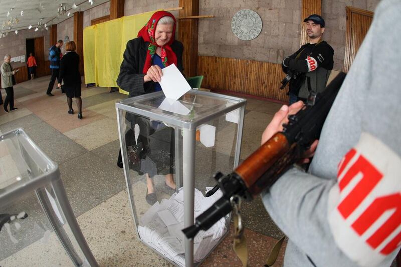 Armed  activists stand guard as a woman casts her ballot in Donetsk on May 11, 2014, for the referendum called by pro-Russian rebels on splitting from the rest of Ukraine. Alexander Khudoteply / AFP