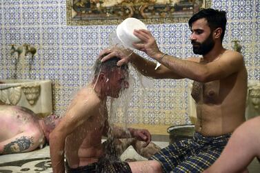 Men bathe at Hammam al-Qawas, a traditional Turkish bathhouse, in Syria's northern city of Aleppo on December 16, 2021.  - With their marble steam rooms, hexagonal fountains and distinctive domes, Aleppo's boathouses have for centuries served as a social hub where men come together to wash up, listen to music and even eat.  But shortages of water, fuel and electricity across war-torn Syria have also turned them into a refuge for those looking for a warm and long bath during winter.  (Photo by AFP)