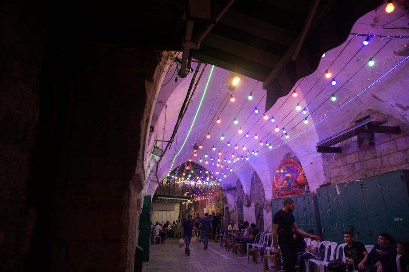 Colorful lights are strung above a cafe where Palestinians smoke water pipes in the Old City of Jerusalem, during the month of Ramadan. AP Photo