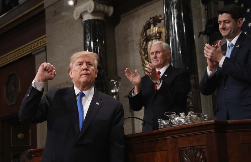 US President Donald Trump, left, gestures at the podium in front of US Vice President Mike Pence, back left and Speaker of the House US Rep Paul Ryan, right, during his first State of the Union address. Win McNamee / Reuters