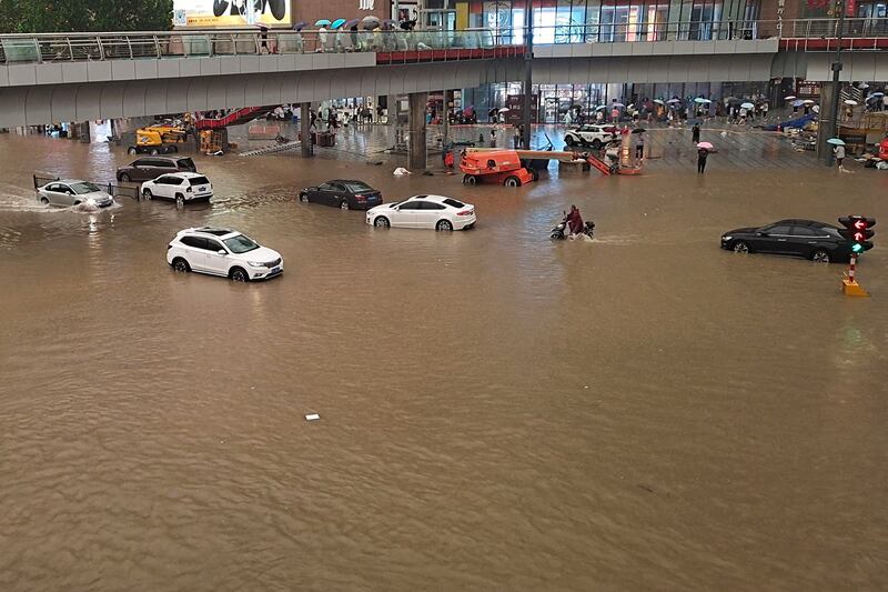 People struggle through flooded streets following heavy rains in Zhengzhou in China's central Henan province.