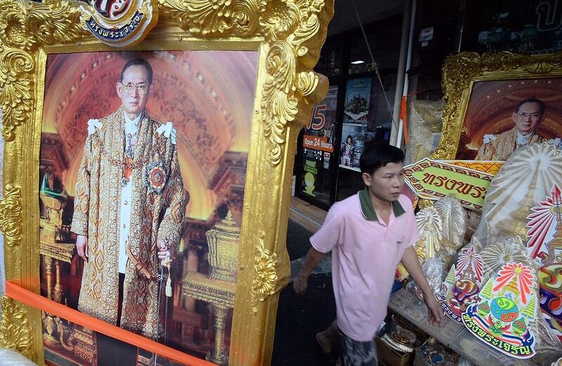 A Thai man walks past paintings of King Bhumibol Adulyadej, who has been treated for “water on the brain” and a chest infection. Indranil Mukherjee / AFP
