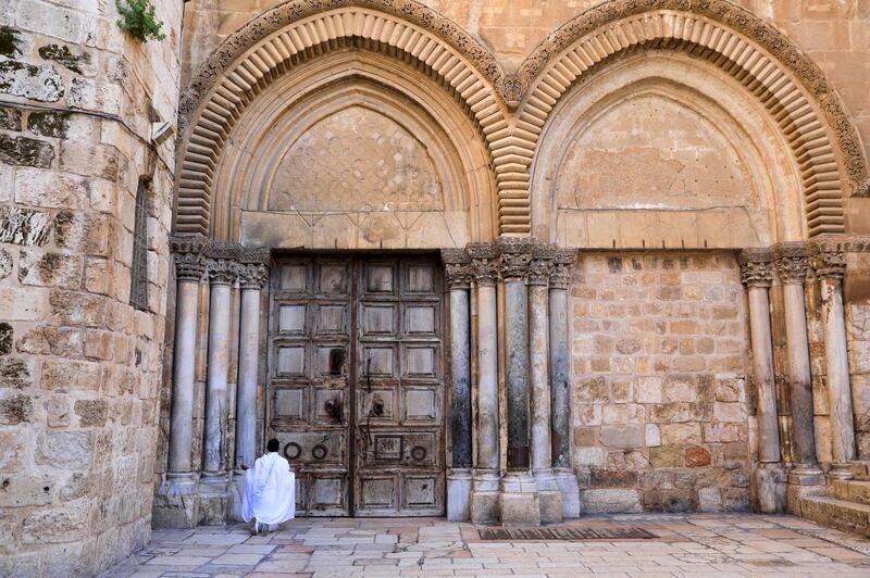 A Christian worshipper prays in front of the closed door of the Church of the Holy Sepulchre before the start of the Easter Sunday service amid the coronavirus diseaseoutbreak, in Jerusalem's Old City.  AFP