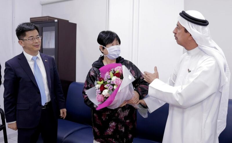 Liu Yujia, center, receives a bouquet of flowers from Dr. Hussein Al Rand, an under-secretary at the Ministry of Health, after she tested negative for the Coronavirus, as Consul General Li Xuhang of China looks on, in Abu Dhabi, United Arab Emirates, Sunday, Feb. 9, 2020. The state-run WAM news agency announced Sunday night that 73-year-old Chinese national Liu Yujia, one of the people infected with the new coronavirus in the Arabian Peninsula nation, â€œhas recovered.â€ (WAM via AP)