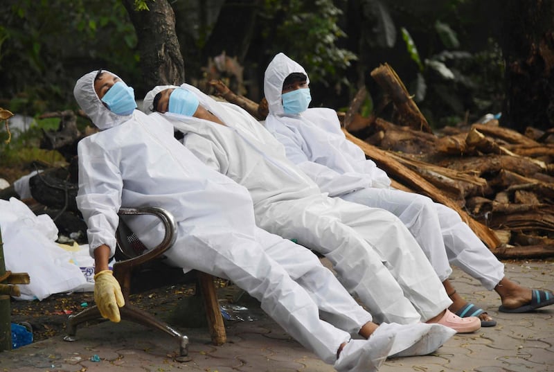 Exhausted ambulance crew members on Covid-19 duties collapse on a bench at a crematorium grounds in Guwahati, north-east India. AFP