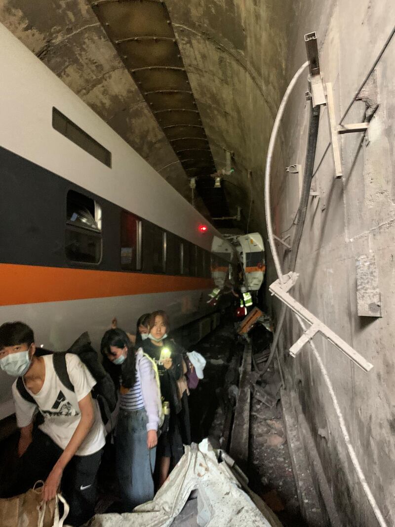 People walk next to a train which derailed in a tunnel north of Hualien, Taiwan, in this handout image provided by Taiwan's National Fire Agency. Reuters