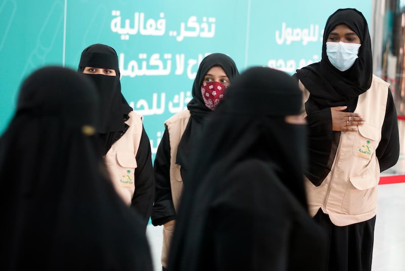 Health workers greet people after they receive their vaccine at a new coronavirus vaccination center, at the Jiddah old airport, Saudi Arabia, Thursday, Jan. 14, 2021. The Saudi Ministry of Health called on citizens and residents to take the vaccine for free. (AP Photo/Amr Nabil)