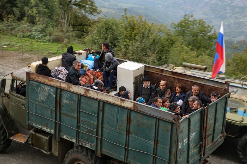 Ethnic Armenians fleeing Karabakh for Armenia sit in a truck at the Lachin checkpoint controlled by Russian peacekeepers and Azeri border guards. EPA