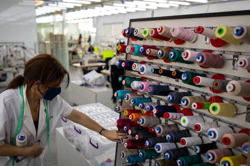 A seamstress looks for thread among the spools on the factory floor.