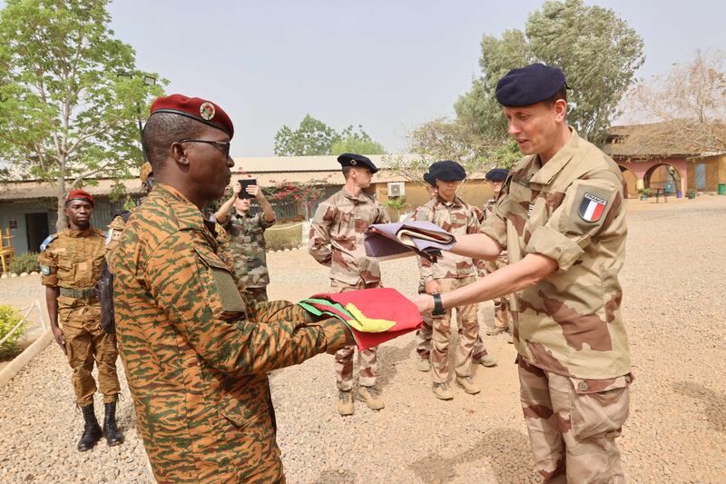 Officers from Burkinabe and French forces hold a flag-lowering ceremony to mark the end of operations by the French army in Burkina Faso. AFP.