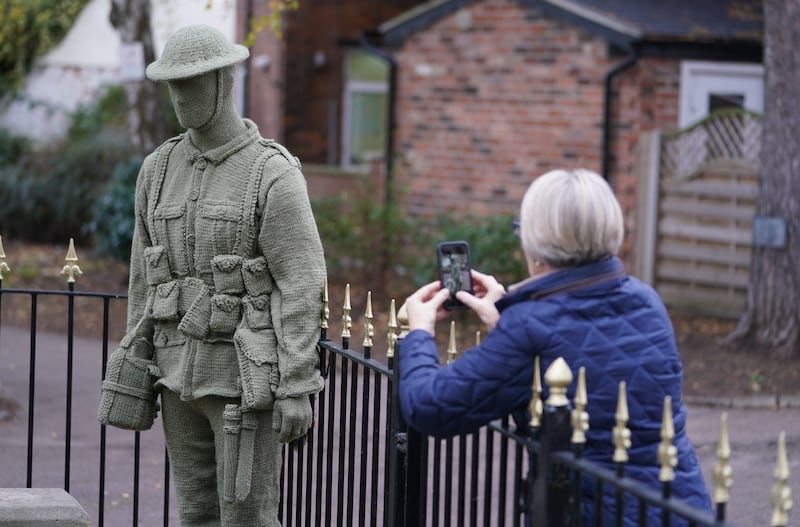 A passer-by looks at a life-sized knitted soldier that has been placed at the War Memorial Clock Tower in Syston, Leicestershire, by an anonymous knitter known only as Knitting Banksy. PA