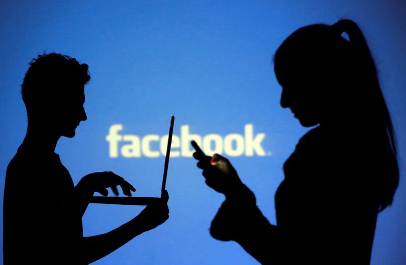 FILE PHOTO: People are silhouetted as they pose with laptops in front of a screen projected with a Facebook logo, in this picture illustration taken in Zenica, October 29, 2014. REUTERS/Dado Ruvic/File Photo