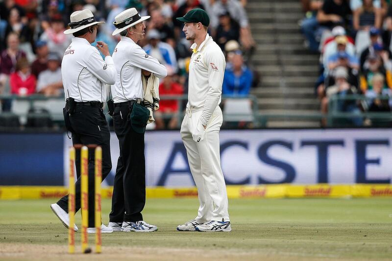 Australian fielder Cameron Bancroft (R) is questioned by Umpires Richard Illingworth (L) and Nigel Llong (C) during the third day of the third Test cricket match between South Africa and Australia at Newlands cricket ground on March 24, 2018 in Cape Town. / AFP PHOTO / GIANLUIGI GUERCIA