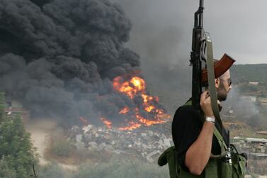 A Lebanese Hizbollah guerrilla looks at a fire rising from a burning object in a Beirut suburb July 17,2006. Israeli Defence Minister Amir Peretz said on Monday that no Israeli jet or helicopter had been shot down over Lebanon but did not rule out that a drone many have been downed.      REUTERS/Issam Kobeisi    (LEBANON)