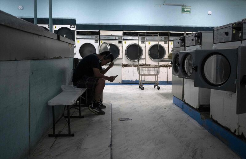 A migrant from Guatemala checks his phone as he waits for his clothes to dry in a launderette in Tijuana, Mexico. AFP