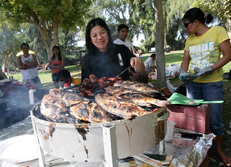 Dubai, United Arab Emirates, Eid Holiday , News desk - ( left) Adela Vellanueve cooks fish and chicken at  Al Safa Park this morning, Nov 6 2011 Beaches and Parks around Dubai started filling up early, thousand of locals will enjoy the extended break due to the Eid Holiday. Mike Young / The National 