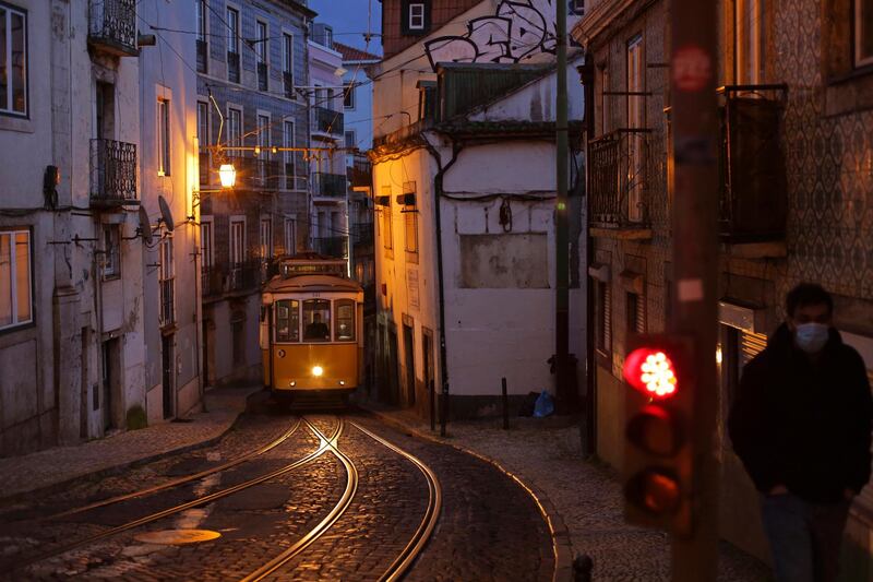 A man walks up a street as a tram drives by in Lisbon's old Alfama neighborhood. AP Photo