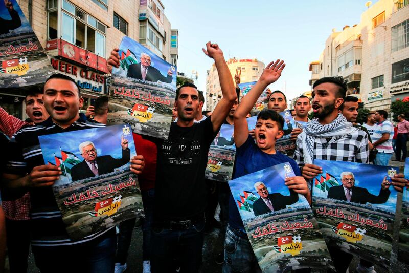 Palestinians chant slogans and wave pictures of Abbas during a demonstration in Ramallah. AFP