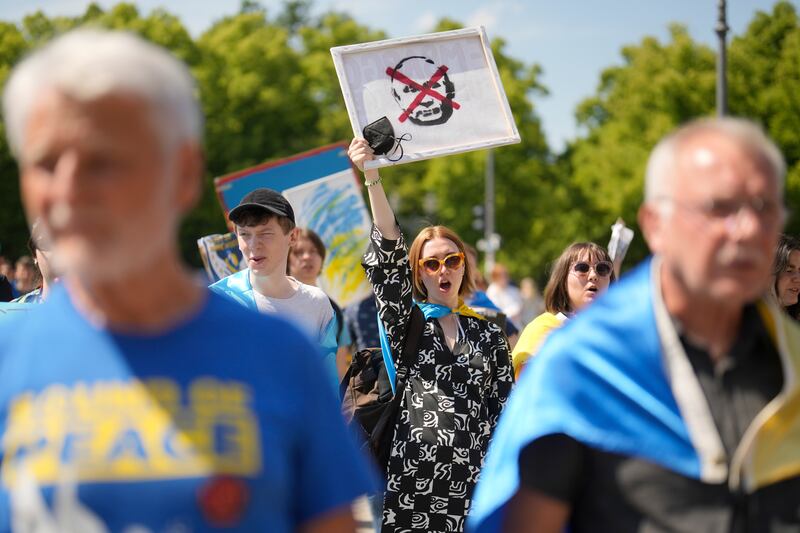 A woman holds a poster showing Russian President Vladimir Putin during a protest against the war in Ukraine at the Brandenburg Gate in Berlin. AP