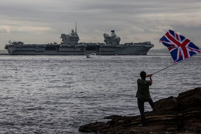 A man waves a British flag as 'HMS Queen Elizabeth' sails out of Tokyo bay in September. Getty Images