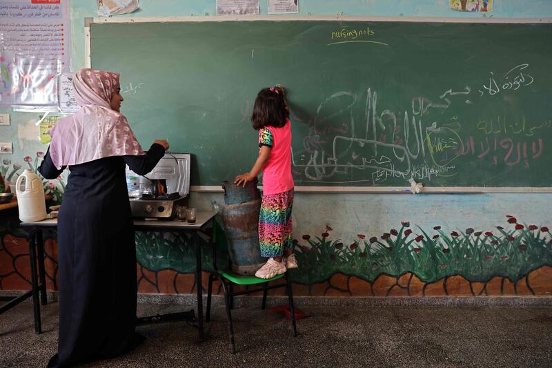 A Palestinian child writes on a blackboard at a school run by the United Nations Relief and Works Agency for Palestine Refugees. Her family are living there temporarily after their home in Gaza city was damaged during the hostilities between Israel and Hamas. AFP