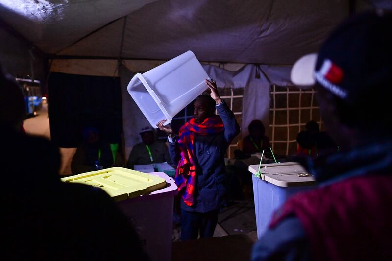 An election official holds up a ballot box to show that it is empty before polls open in Kibera. AFP