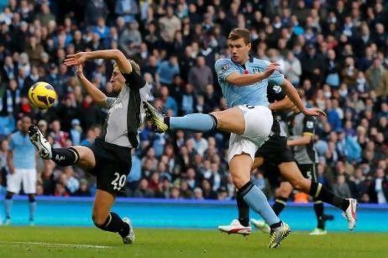 Manchester City's Edin Dzeko shoots past Tottenham Hotspur's Michael Dawson to score his side's winner at Etihad Stadium yesterday.