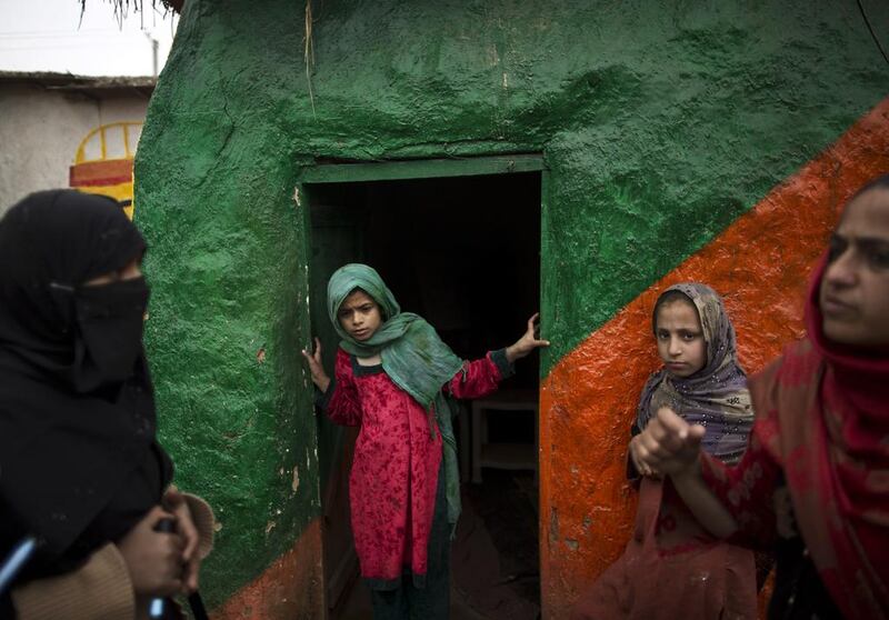 A Pakistani health worker, left, checks with a teacher if schoolchildren need a polio vaccine, at a makeshift school on the outskirts of Islamabad, Pakistan. Muhammed Muheisen / AP Photo