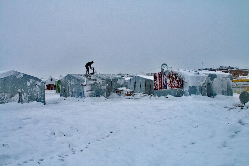 A Syrian man clears snow off his tent at a refugee camp in Lebanon's eastern Bekaa valley on January 16, 2019. Lebanon hosts an estimated 1.5 million Syrian refugees, many of whom live in informal settlements that have little or no infrastructure. / AFP / -
