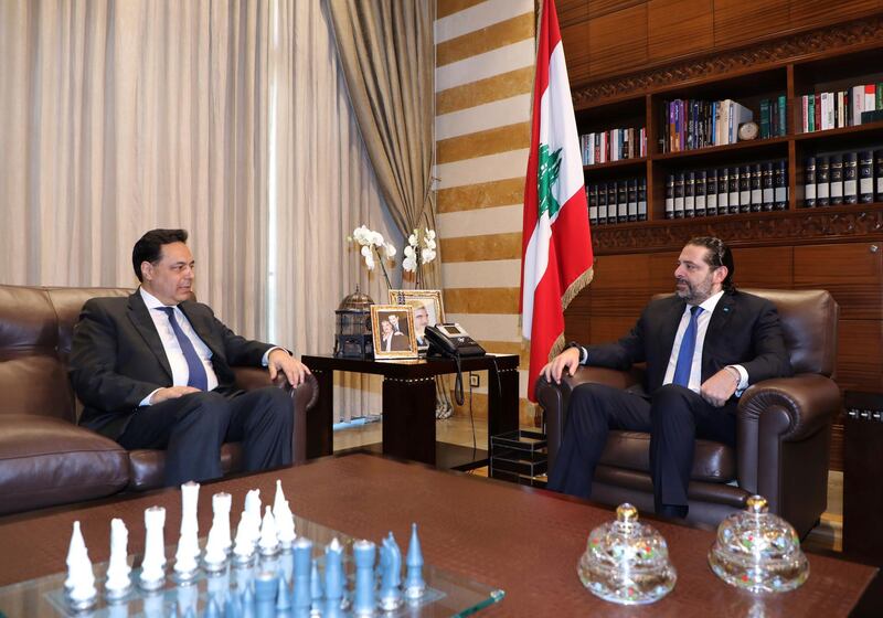 In this photo released by Lebanon's official government photographer Dalati Nohra, Lebanese Prime Minister-designate Hassan Diab, left, meets with outgoing Prime Minister Saad Hariri, in Beirut, Lebanon.  AP