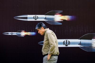 A man walks past a banner depicting missiles along a street in Tehran on April 19. AFP