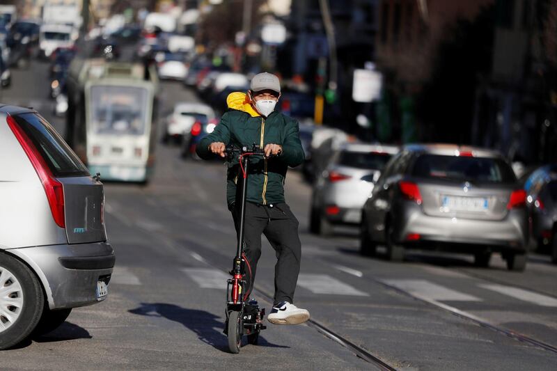 A man wearing a protective mask rides an electric scooter along the street in Rome, Italy. Reuters