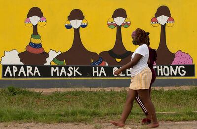 FILE â€” In this Thursday, Jan. 28, 2021 file photo, a woman walks past a coronavirus-themed mural promoting the use of face mask in public to protects against COVID-19 in Vereeniging, South Africa. A special unit in South Africa is investigating nearly $900 million worth of government procurement contracts related to the coronavirus pandemic for possible corruption. (AP Photo/Themba Hadebe, file)