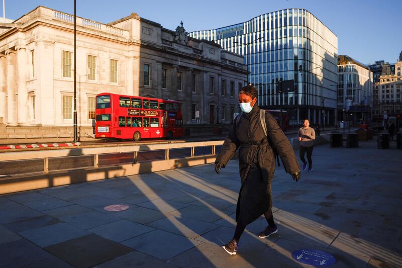 A woman wearing a face mask crosses London Bridge. Reuters