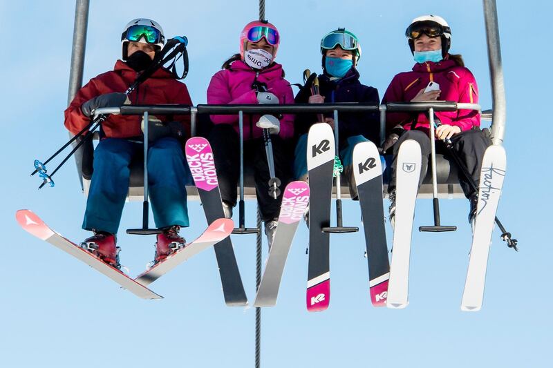 FILE - In this Oct. 30, 2020 file photo skiers wearing face masks riding a chairlift on the opening day of the Verbier ski area in the Swiss Alps,  EU member states Austria, France, Germany and Italy are shutting or severely restricting access to the slopes this holiday season amid COVID-19 concerns, Switzerland is not.   (Jean-Christophe Bott/Keystone via AP, File)