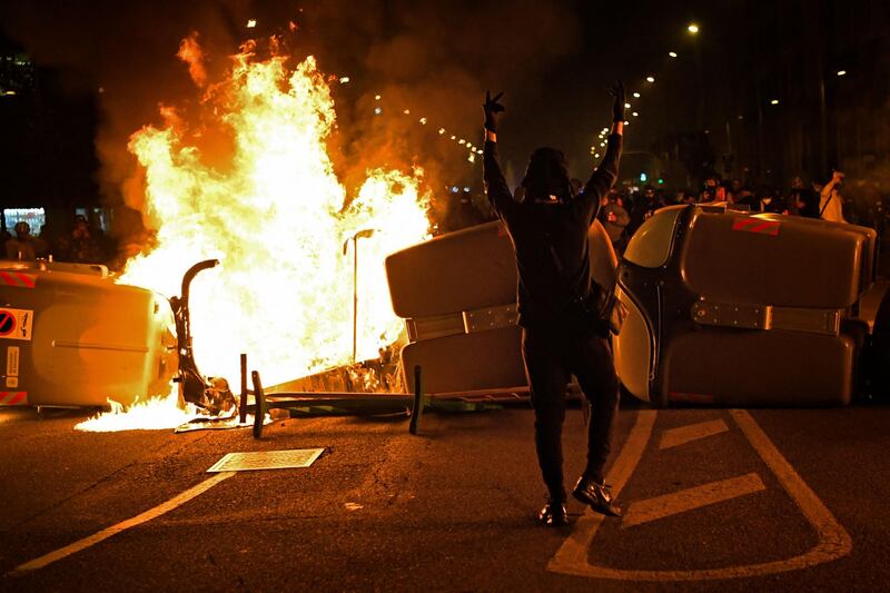 A protester gestures in front of trash containers in flames during clashes with Catalan regional police forces. AFP