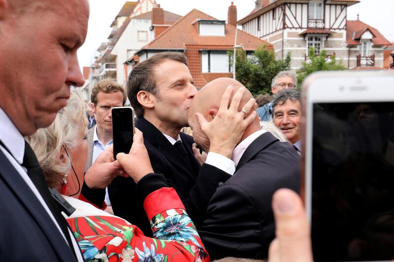 French President Emmanuel Macron kisses the head of a wellwisher after casting his ballot in Le Touquet, France. Reuters