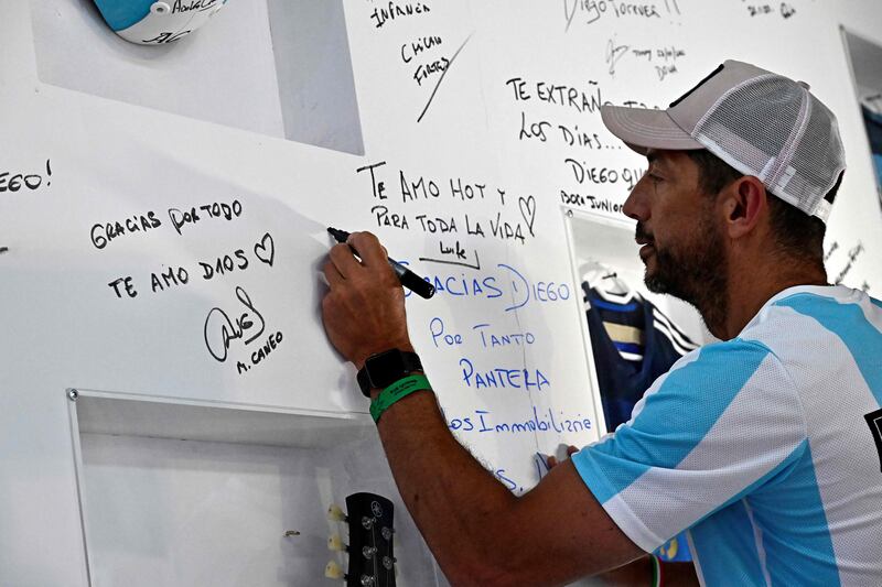 A fan writes a message on a wall honouring the life of Argentina football legend Diego Maradona. AFP