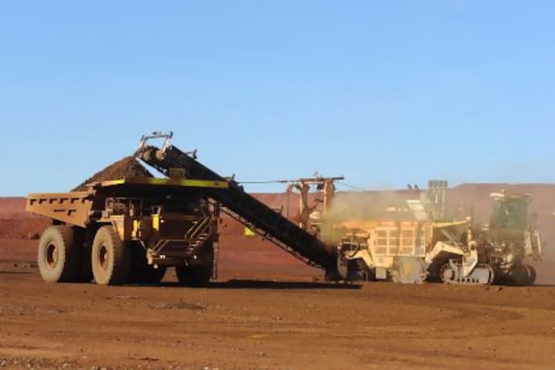 An earth mover receives a load of iron ore from a surface miner in the mine pit at Fortescue Metals Group's Cloudbreak operation in the Pilbara region of Western Australia.