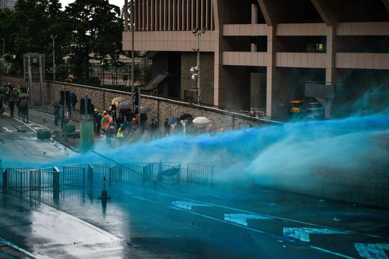 Police fire a water cannon towards protesters near the government headquarters in Hong Kong.   AFP