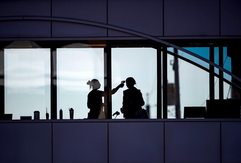 A healthcare worker takes the temperature of a visitor to Essentia Health in Duluth, Minnesota. Star Tribune via AP