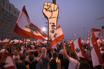 This picture taken on November 10, 2019 shows protesters waving Lebanese national flags by a giant sign of a fist with the slogan "revolution" written on it in Arabic in the capital Beirut's Martyrs' Square during continuing anti-government protests.  / AFP / Amir Makar                                                                                                                                                                                                                                                     
