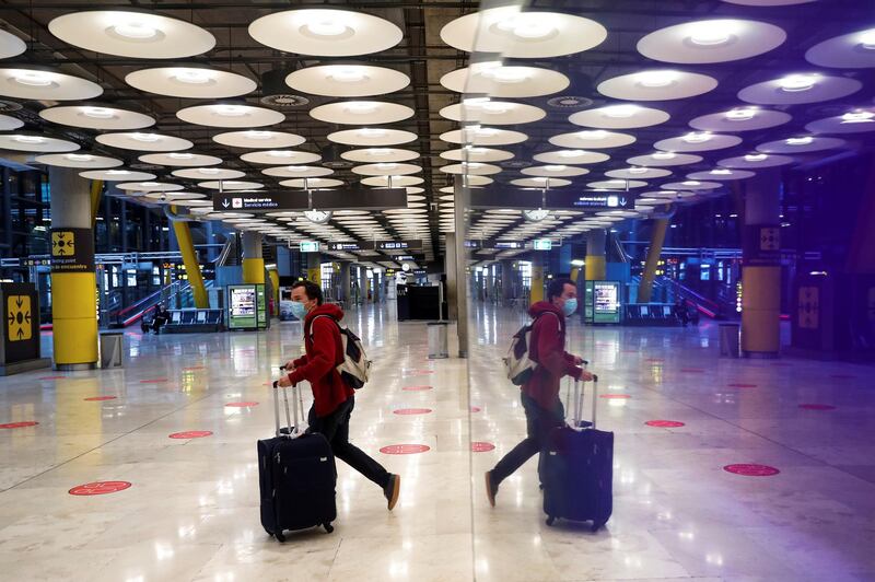 A traveler is reflected on a surface as he pushes his luggage through the arrivals hall at Adolfo Suarez-Barajas airport in Madrid. EPA