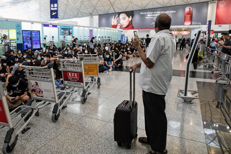 A passenger stands with his luggage as demonstrators block a departure hall during the protest at the Hong Kong International Airport. Bloomberg
