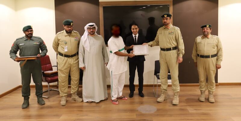 A prisoner receives a certificate from Dubai Police officers and officials after completing a car mechanic training course. Photo: Dubai Police