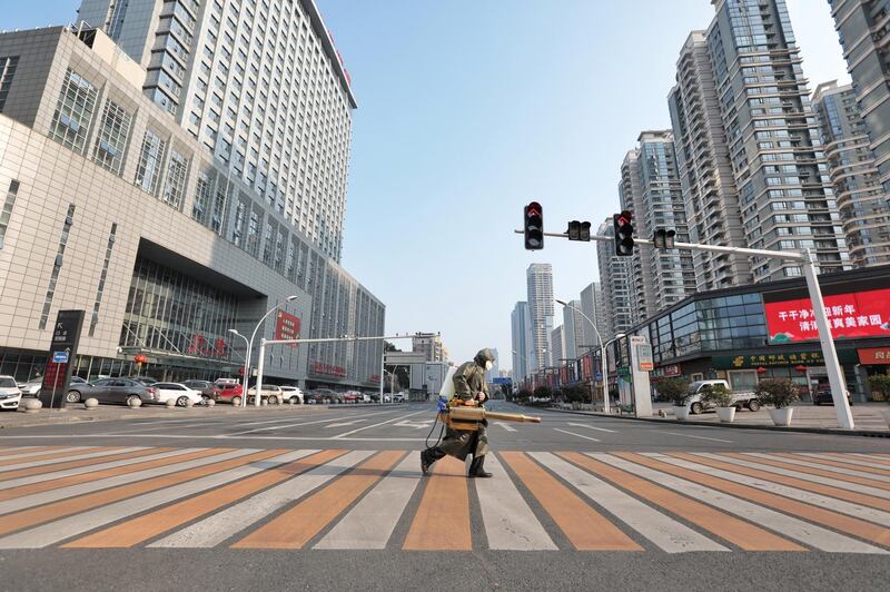 A worker with sanitizing equipment crosses the road in front of a hospital in Yichang city of Hubei, the province hit hardest by the novel coronavirus outbreak, China February 12, 2020. Picture taken February 12, 2020. China Daily via REUTERS ATTENTION EDITORS - THIS IMAGE WAS PROVIDED BY A THIRD PARTY. CHINA OUT.      TPX IMAGES OF THE DAY