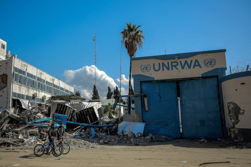People walk past the damaged Gaza city headquarters of the UNWRA. AFP